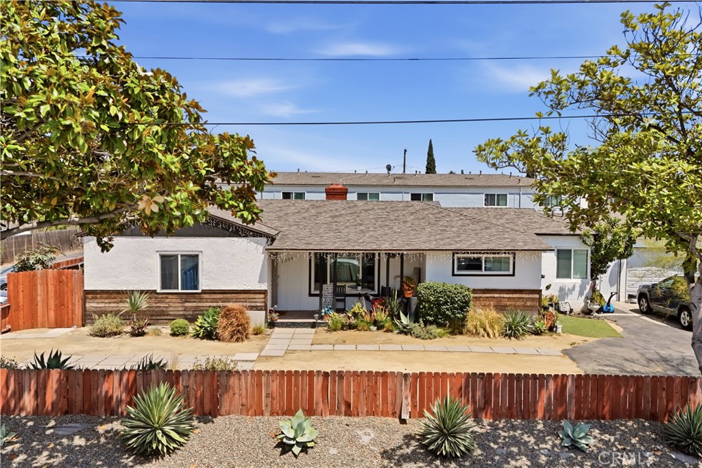 Single-story house with a covered porch, red fence, and drought-tolerant front landscaping.