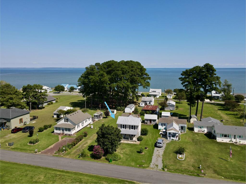 Aerial view of the marked coastal home beside the water, among neighboring houses and lawns.