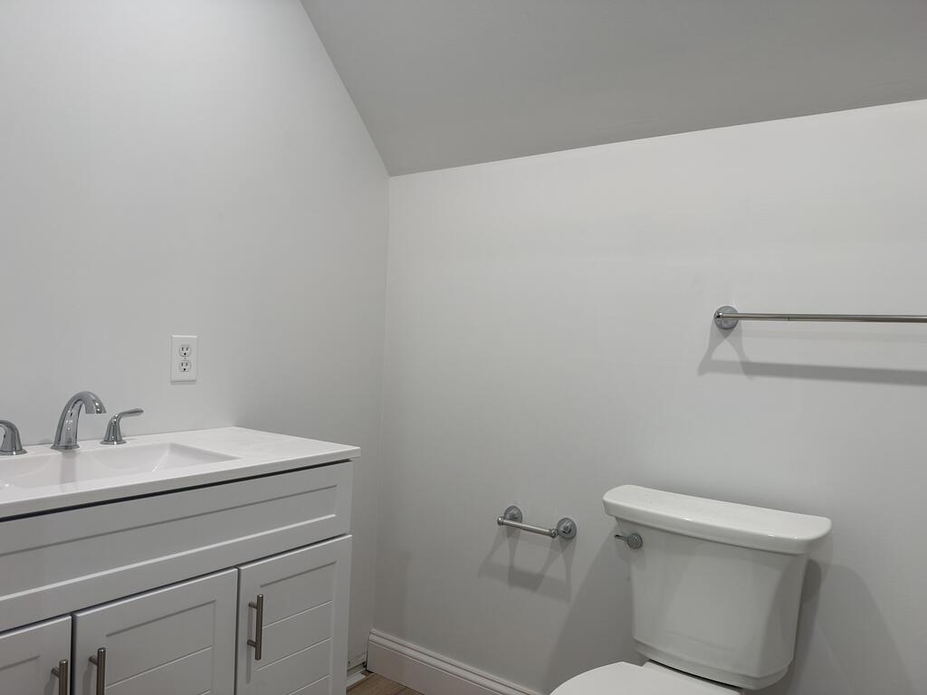 Bathroom with a white vanity and sink beside a toilet, with chrome fixtures.