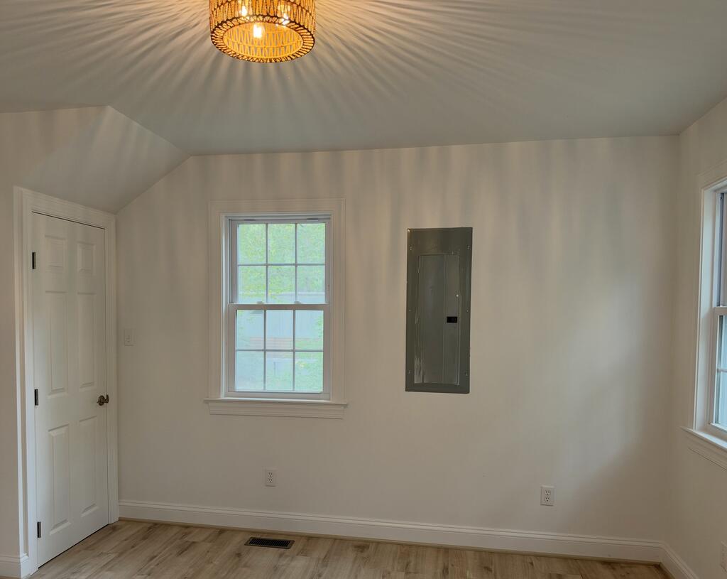 Vacant room with two windows, wood-look flooring, and a woven ceiling light.