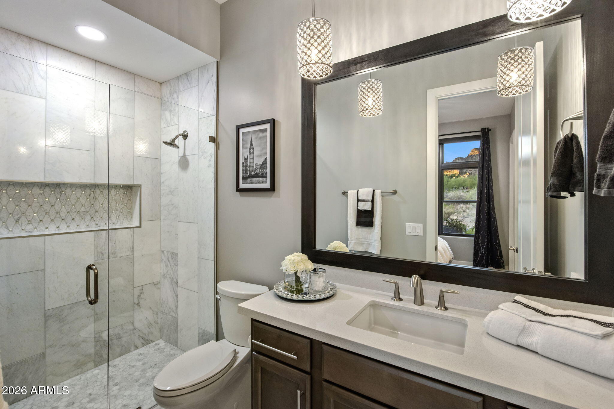 Bathroom with marble shower, mosaic niche, dark wood vanity, and oversized mirror.