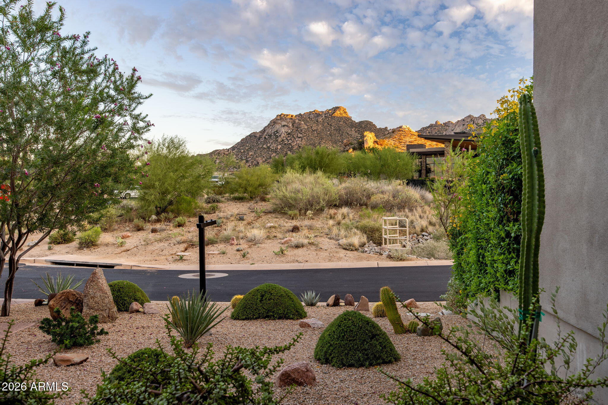 Desert landscaping and a rocky mountain view across the street from the home.