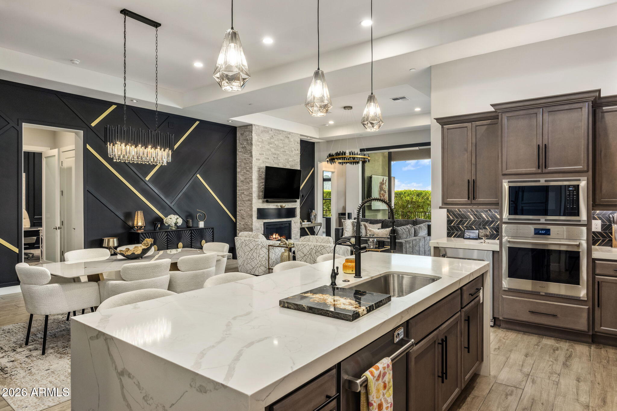 Open-plan kitchen with a large white stone island, dark cabinets, and adjoining living and dining areas.