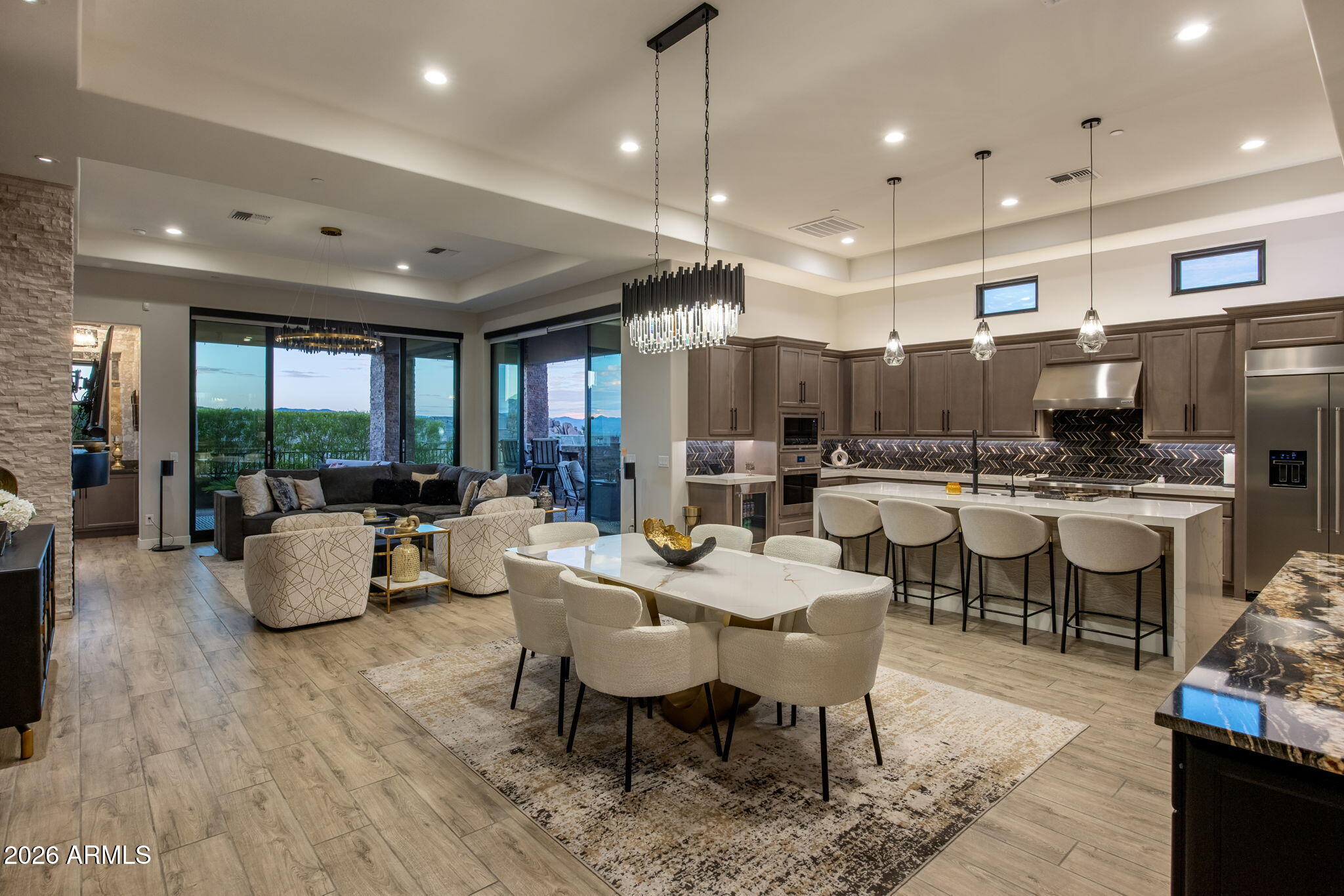 Open-plan kitchen and dining room with dark cabinetry, a large island, and mountain views through sliding glass doors.