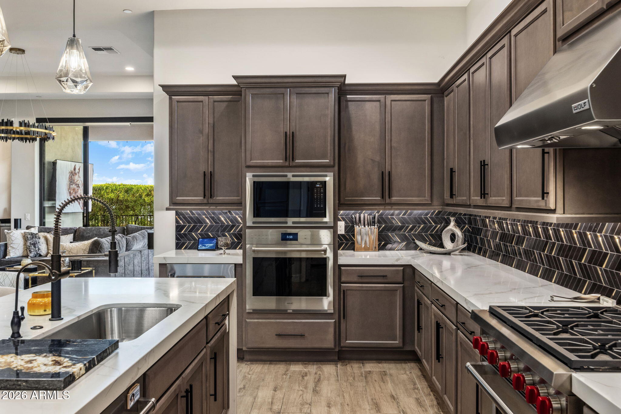 Modern kitchen with dark cabinetry, geometric tile backsplash, and stainless steel appliances.
