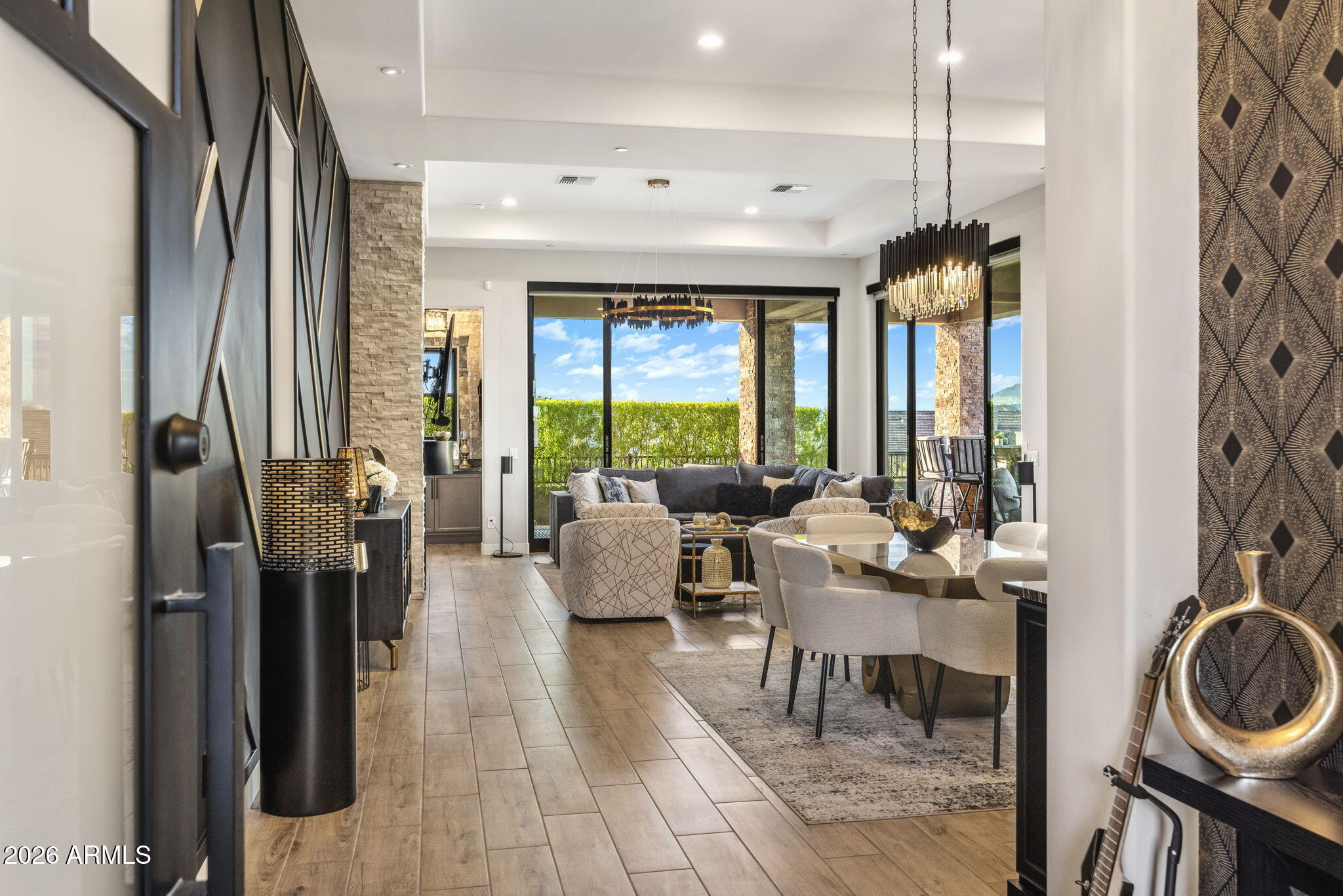Open-plan living and dining room with a dark sectional, cream chairs, and large windows facing the patio.