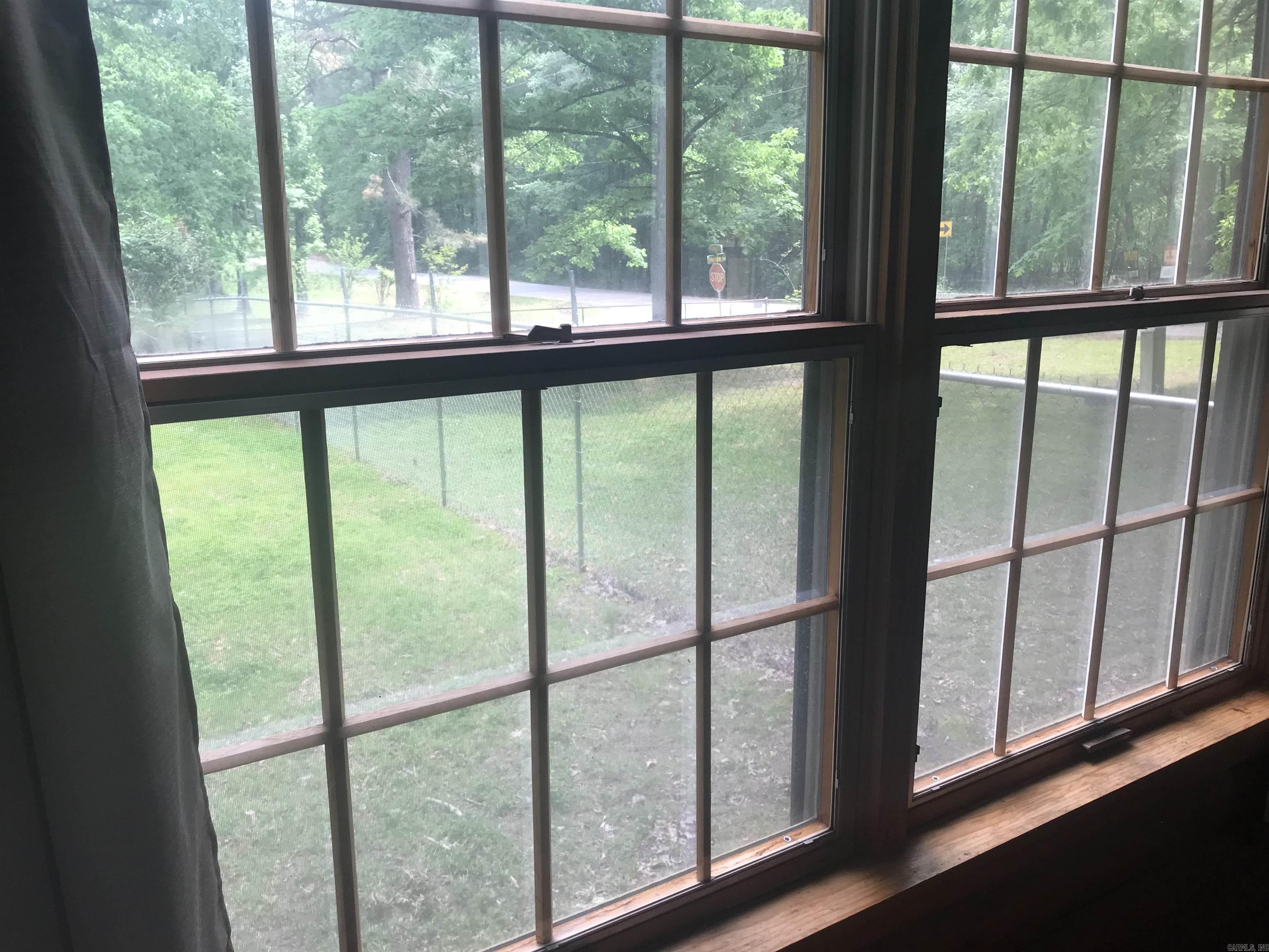 Large divided-light windows overlook a fenced lawn and leafy trees.