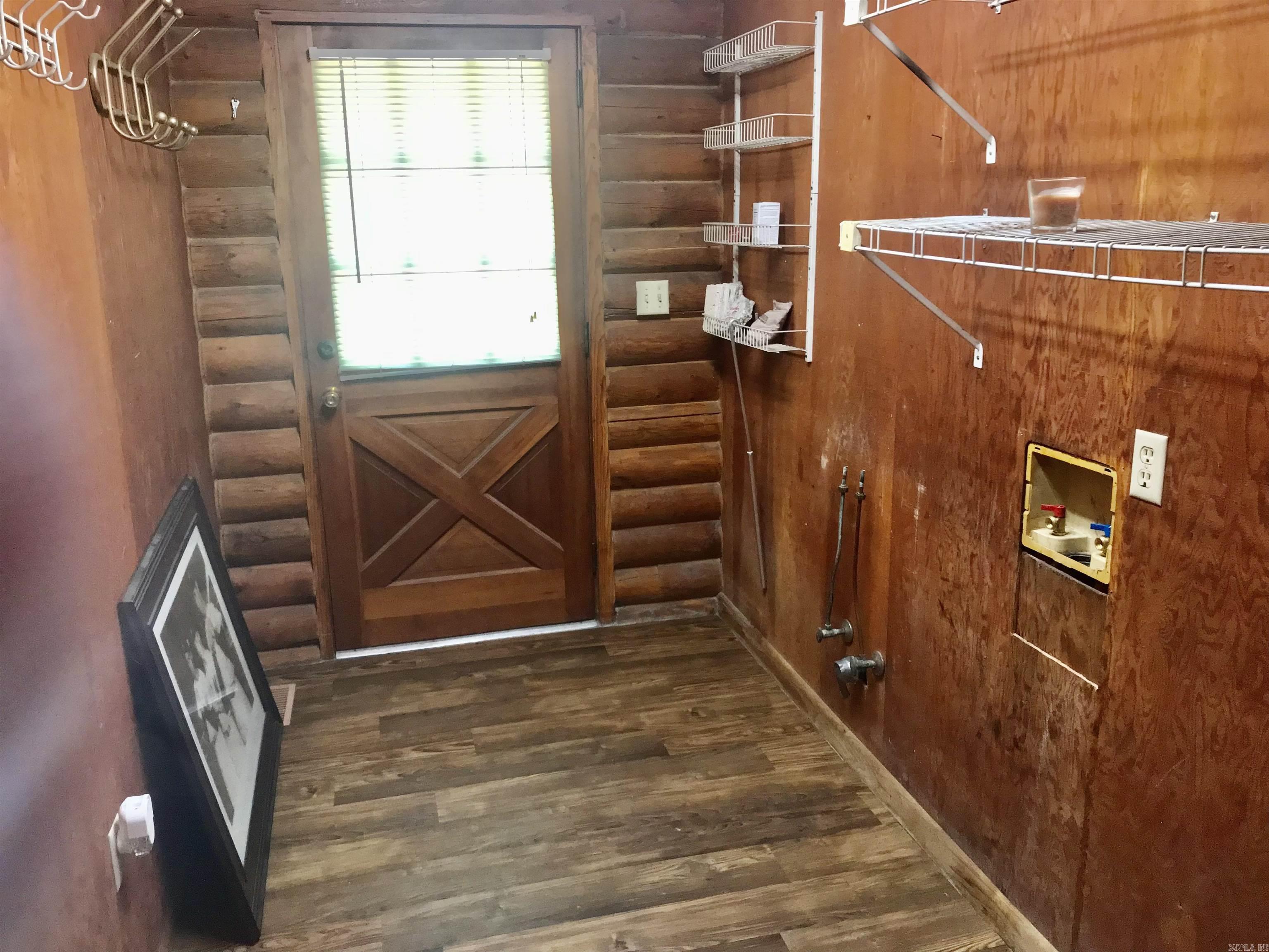 Wood-paneled utility room with wire shelves, laundry hookups, and a cross-braced door with a window.