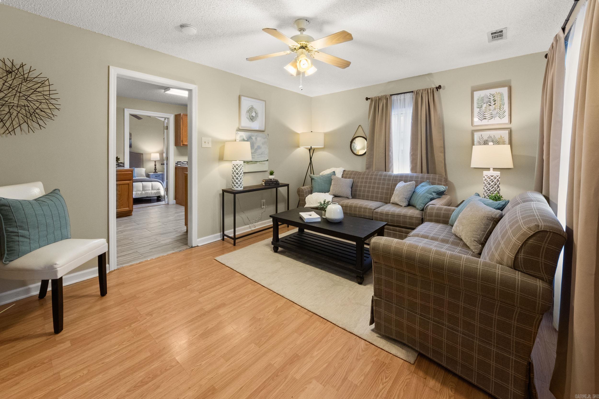 Furnished living room with plaid sofas and a doorway to a bedroom.