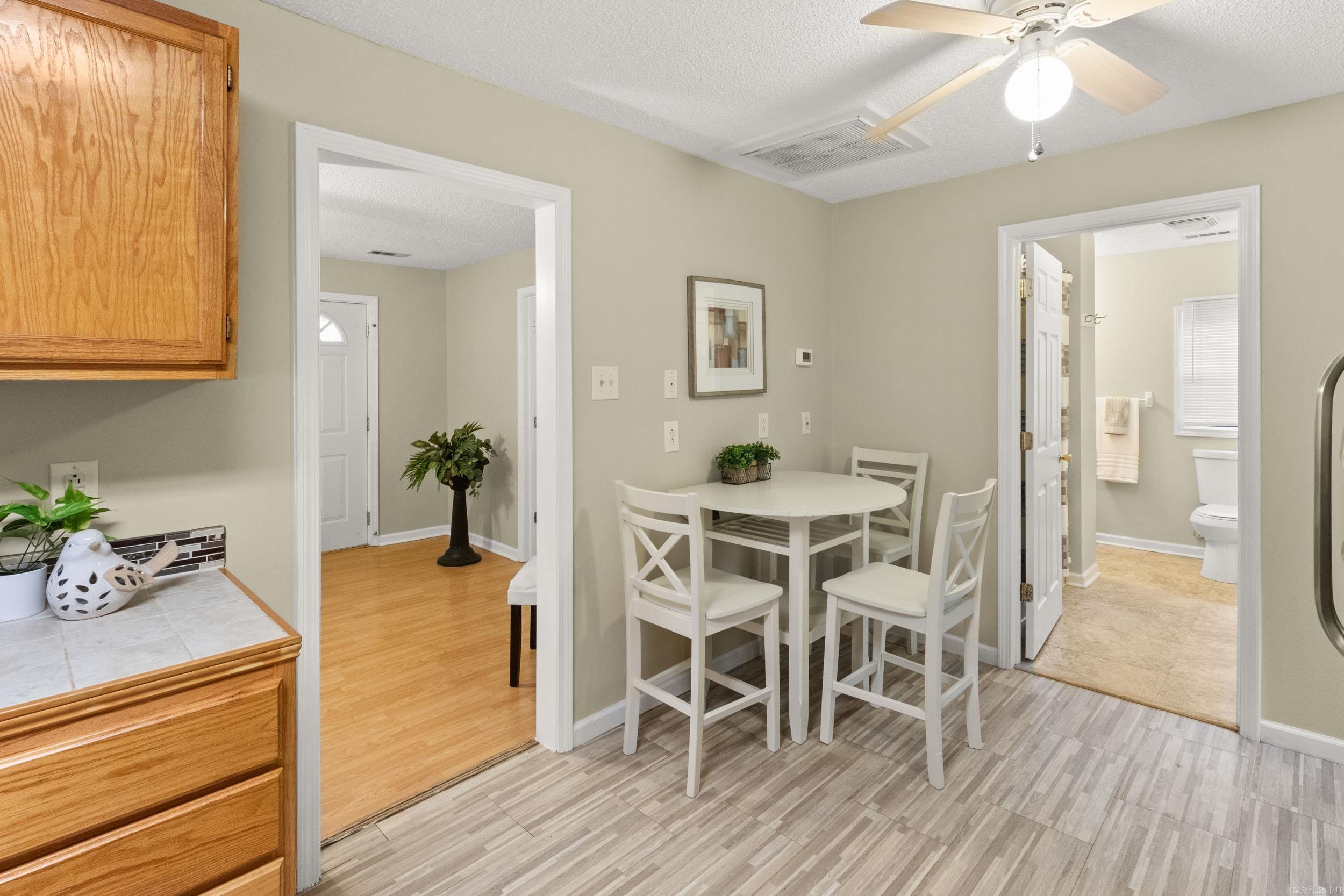 Kitchen dining area with a white table and chairs beside an open bathroom doorway.