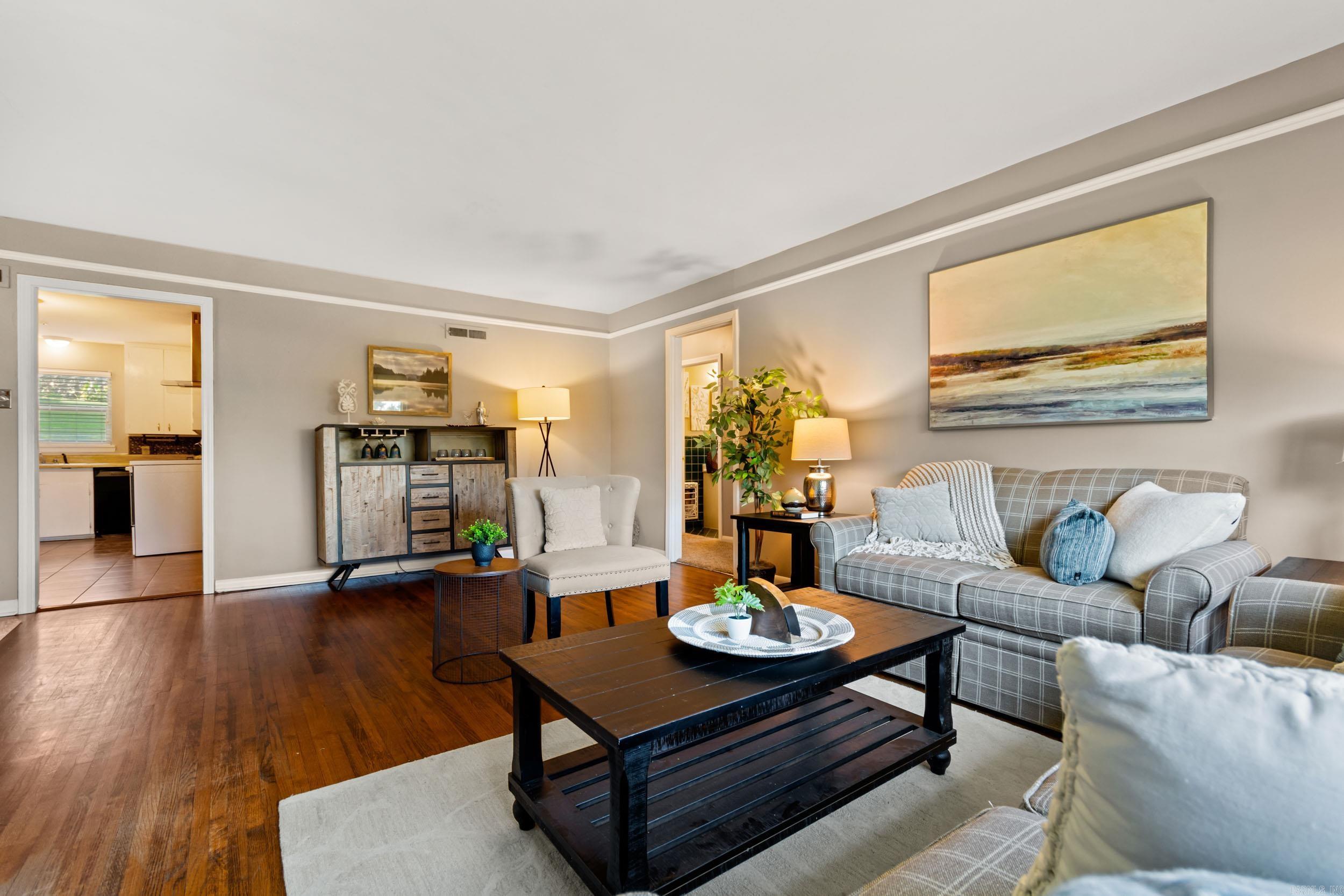 Staged living room with gray plaid sofas, a dark coffee table, and hardwood floors.