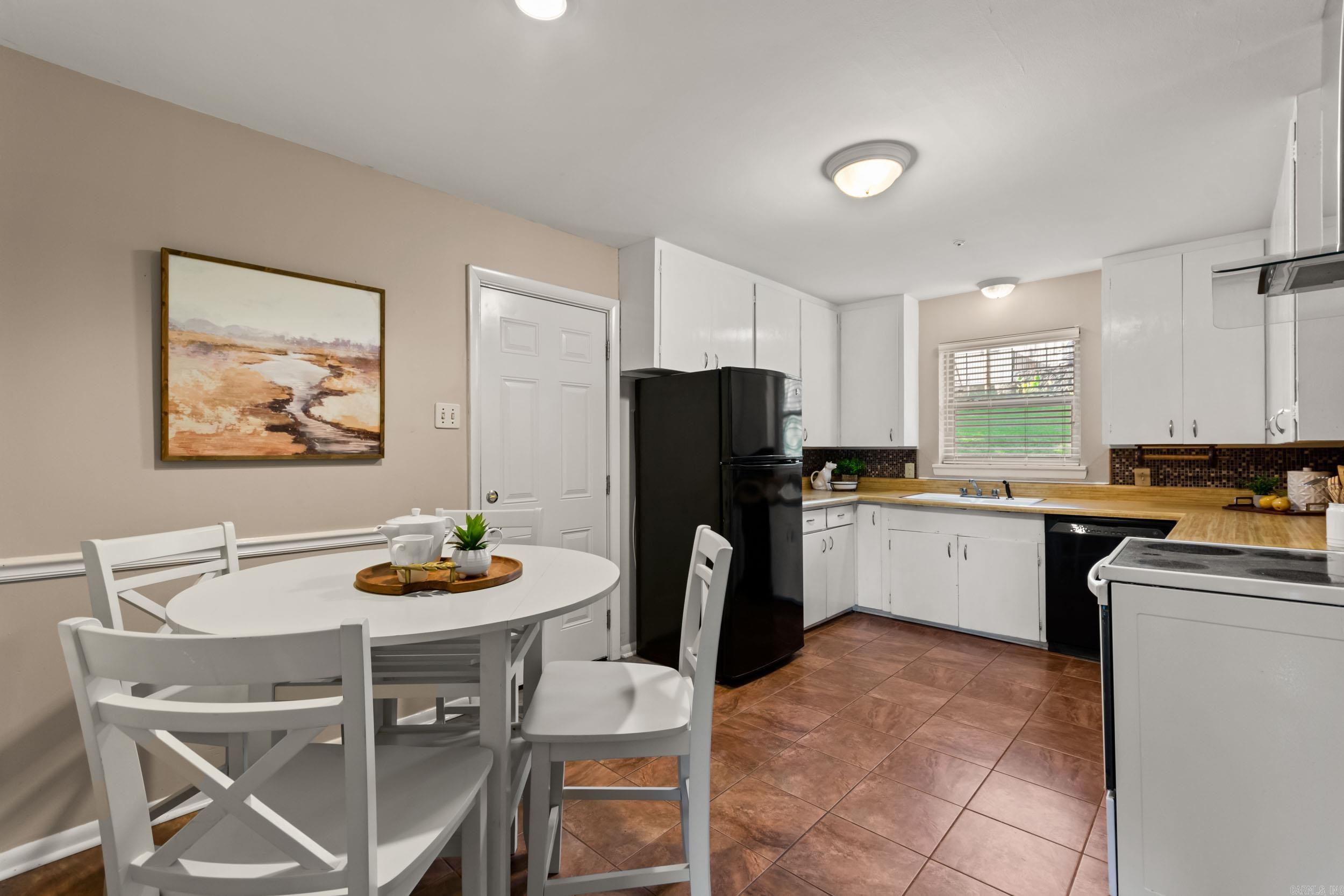 Kitchen and dining area with white cabinetry, wood countertops, and a white table and chairs.