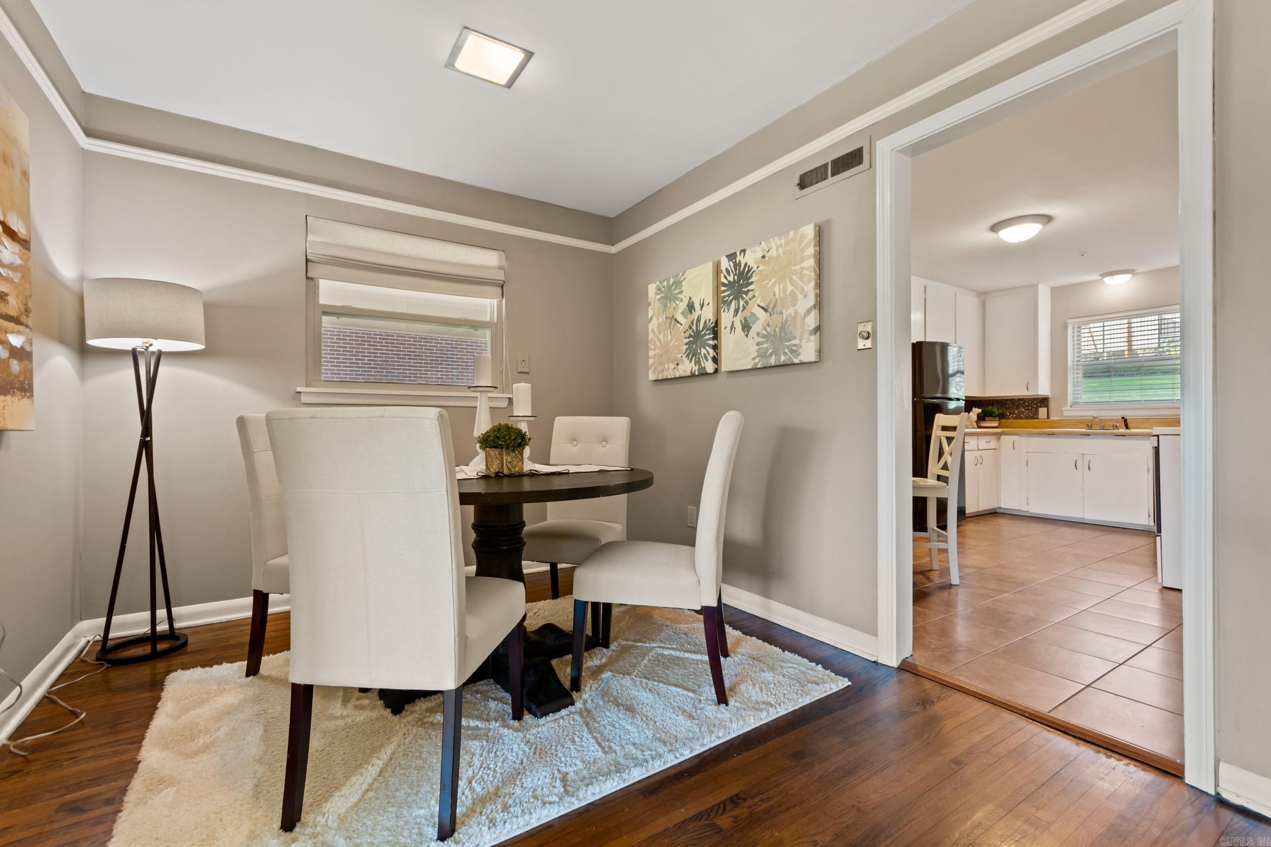Staged dining room with white upholstered chairs and a round table beside the kitchen.