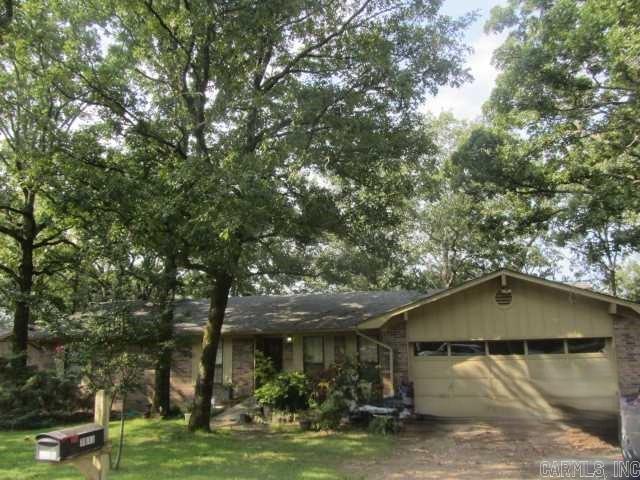 Single-story home with a two-car garage beneath mature shade trees.