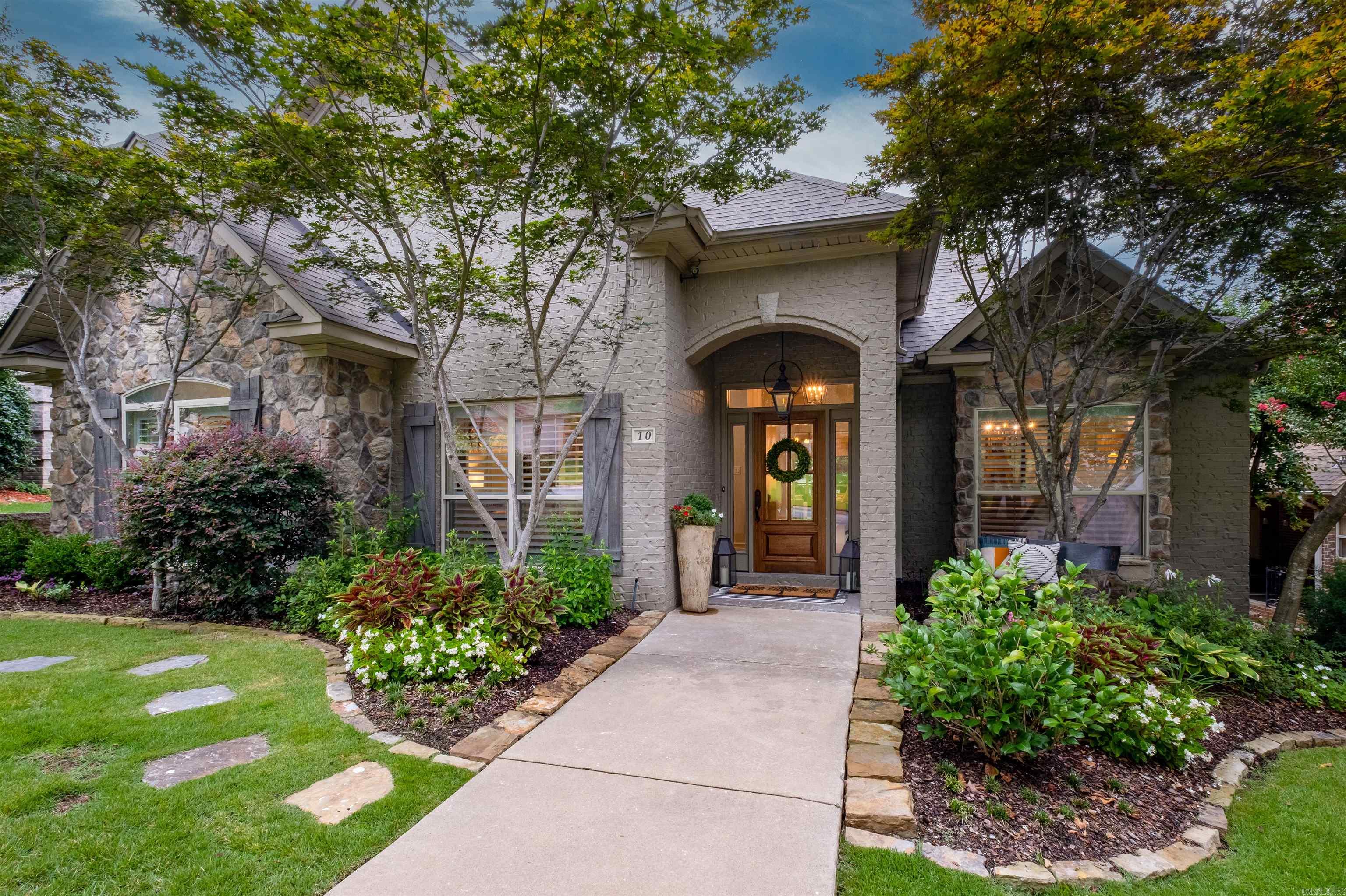 House front with stone accents, landscaped gardens, and an arched entry marked 10.