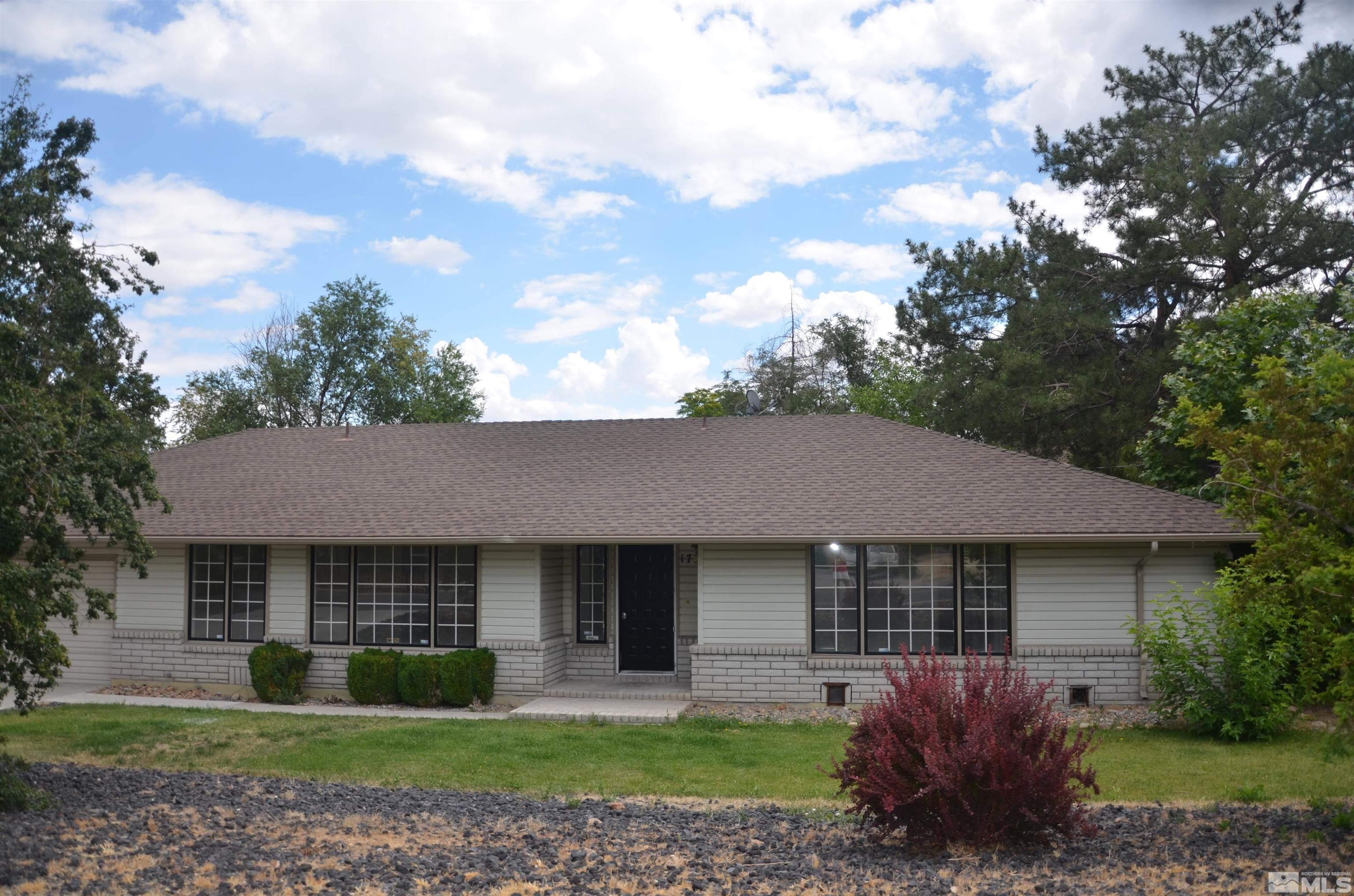 Single-story home with a brick lower facade, broad shingle roof, and landscaped front lawn.