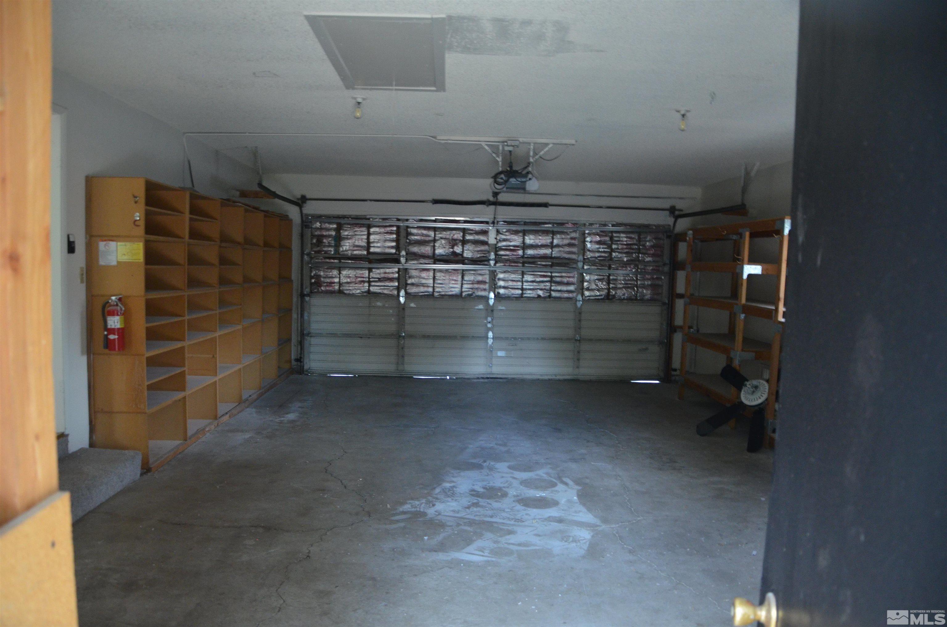 Garage with built-in wooden shelving, a closed overhead door, and a concrete floor.