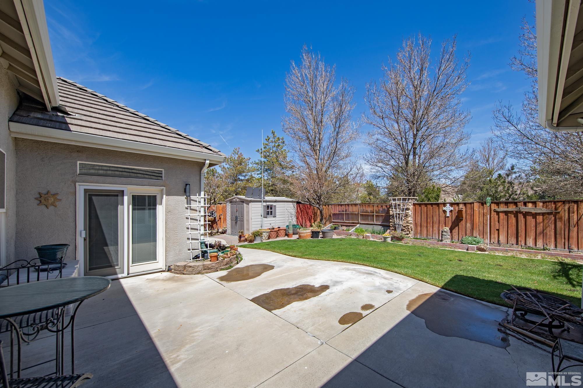 Backyard patio and lawn with raised garden beds, a storage shed, and wood privacy fencing.