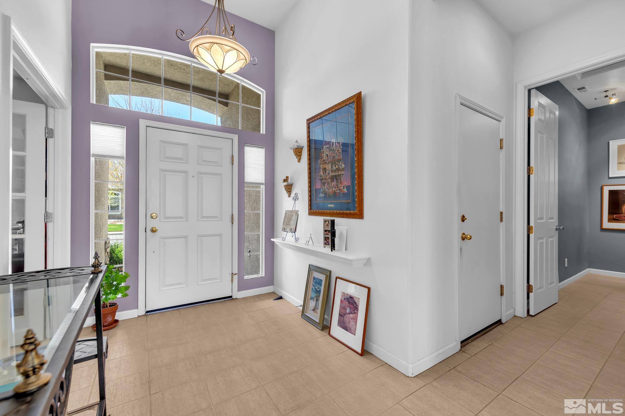 Entry foyer with a tall window above the front door, lavender accent wall, and chandelier.