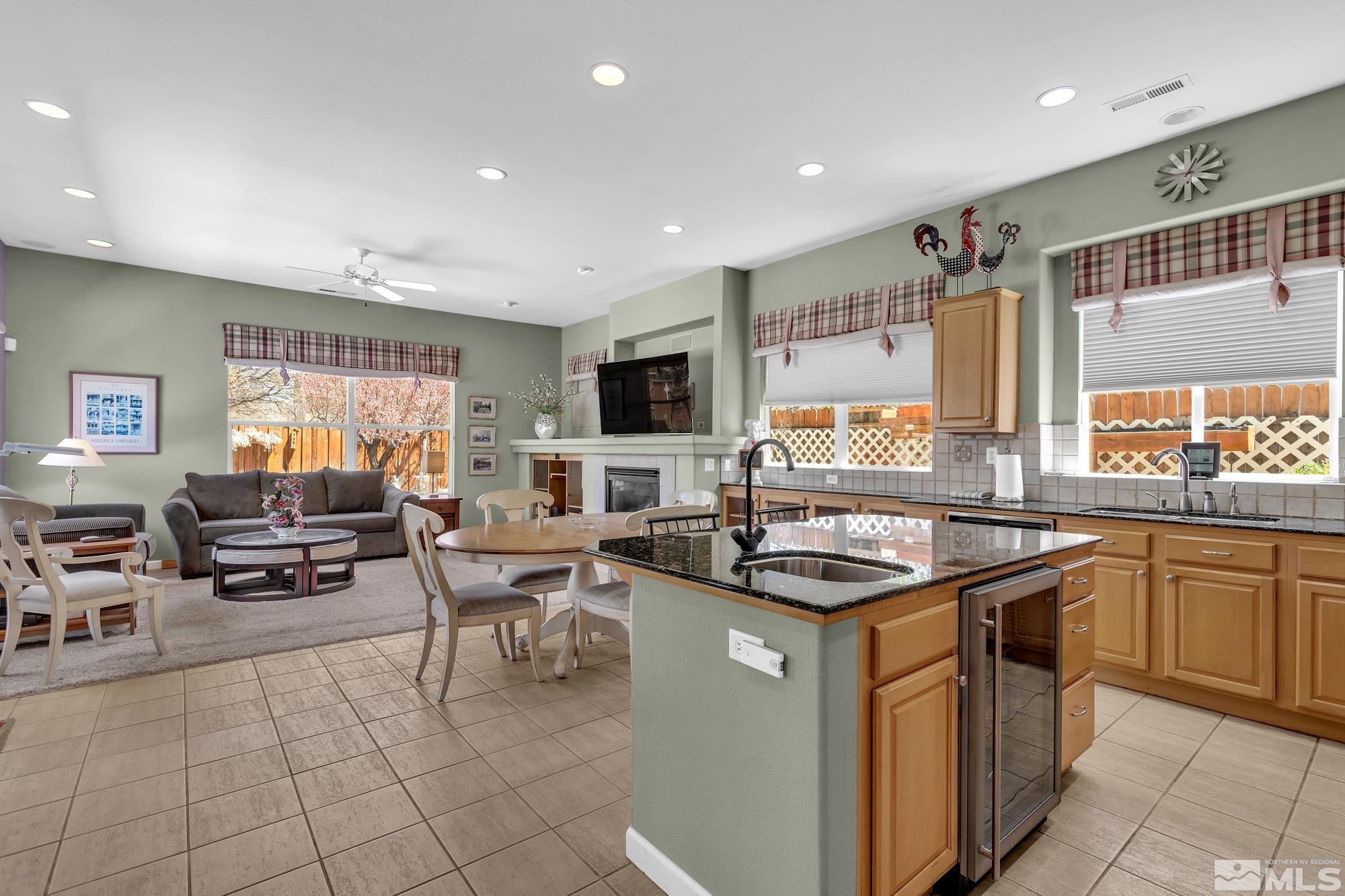 Open kitchen with black stone island, dining area, and adjoining living room.