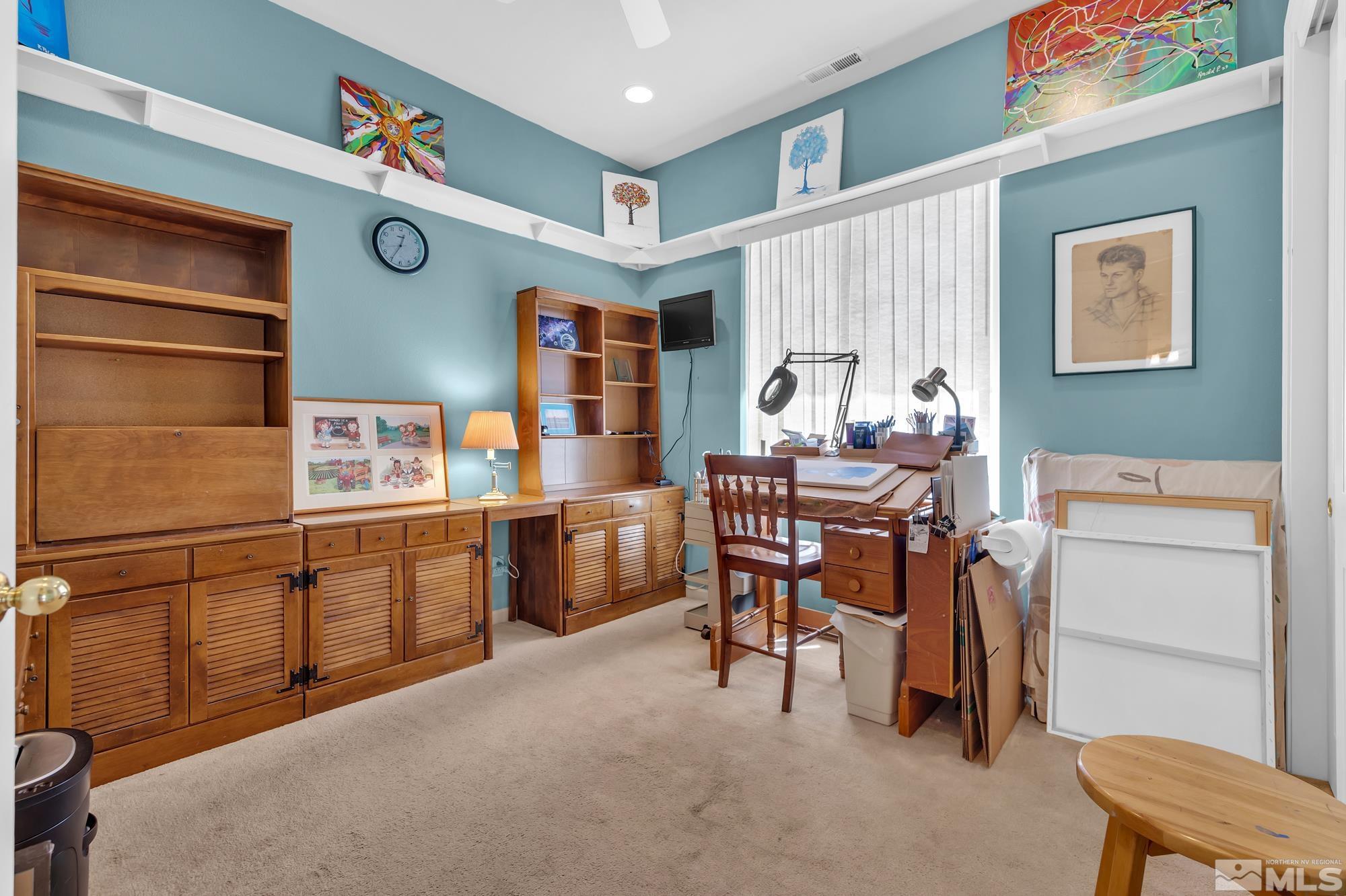 Home office with wooden built-ins, a drafting desk, and colorful artwork on blue walls.