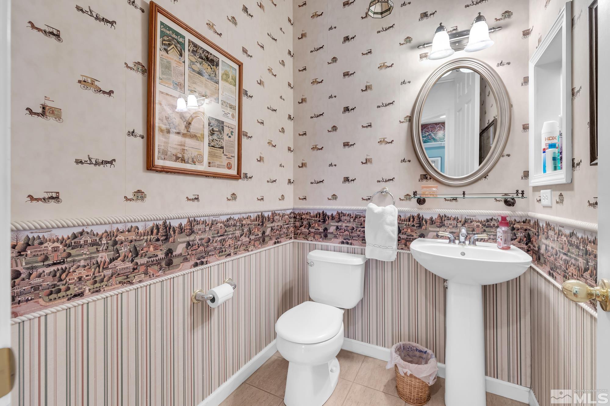 Bathroom with horse-and-carriage wallpaper, a village border, striped wainscoting, and a white pedestal sink.