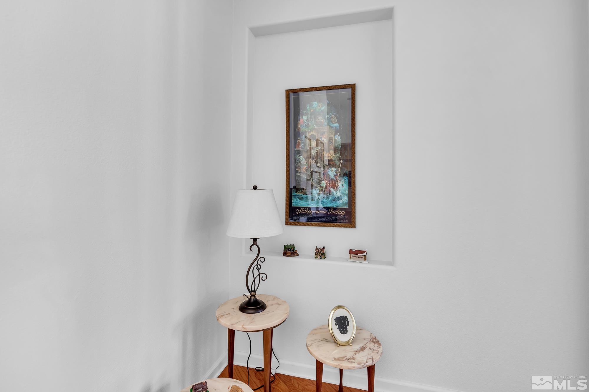 Interior nook with marble-top tables, a decorative lamp, and framed Shakespearean Fantasy artwork.