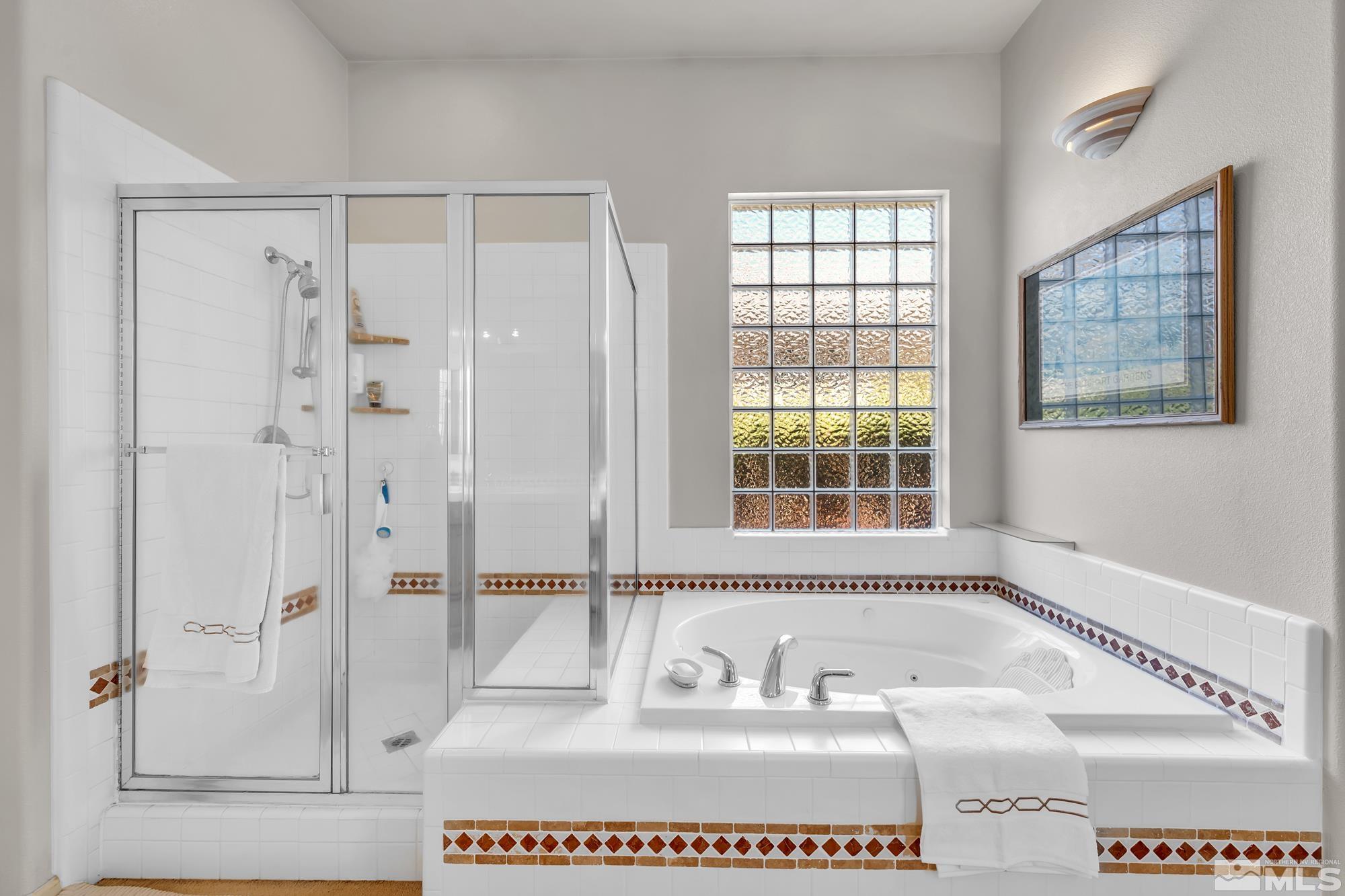 Bathroom with a glass shower and jetted tub beneath a textured glass-block window.