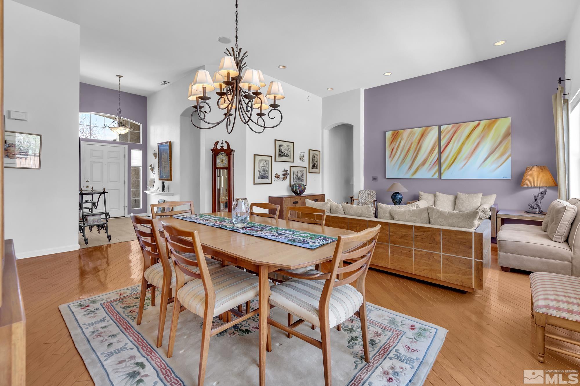 Open dining and living room with a large wooden table, cream sofas, and a purple accent wall.