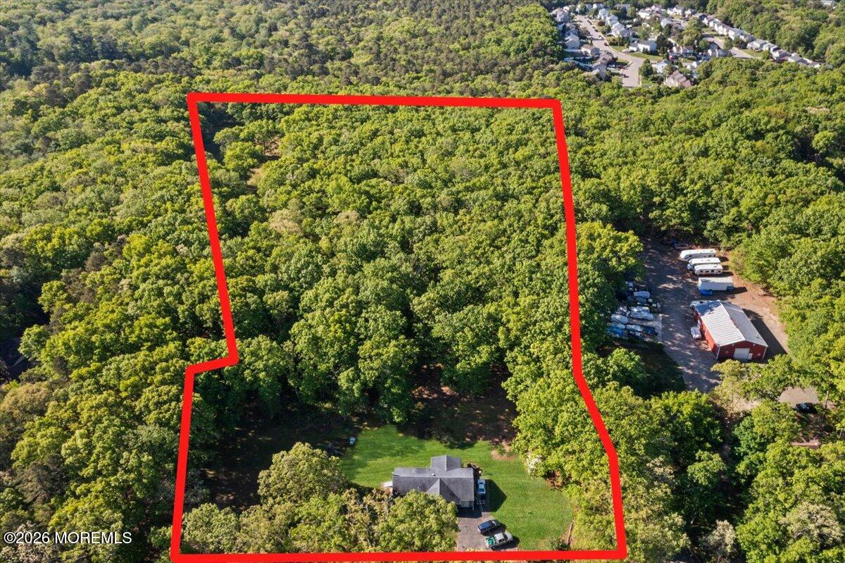 Aerial view of wooded land outlined in red, with a house near the bottom.