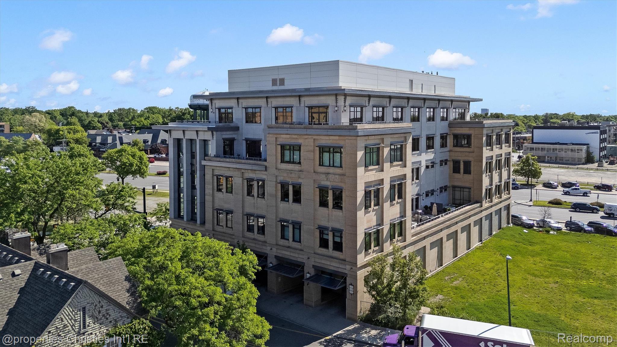 Modern multi-story commercial building with a stone facade and upper-level terraces, viewed from above.