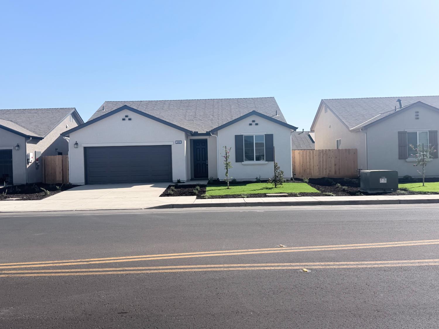 Single-story home with a dark two-car garage, driveway, and small front lawn.
