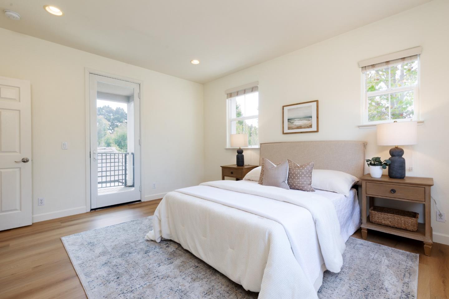 Staged bedroom with a white bed and glass door opening to a balcony.