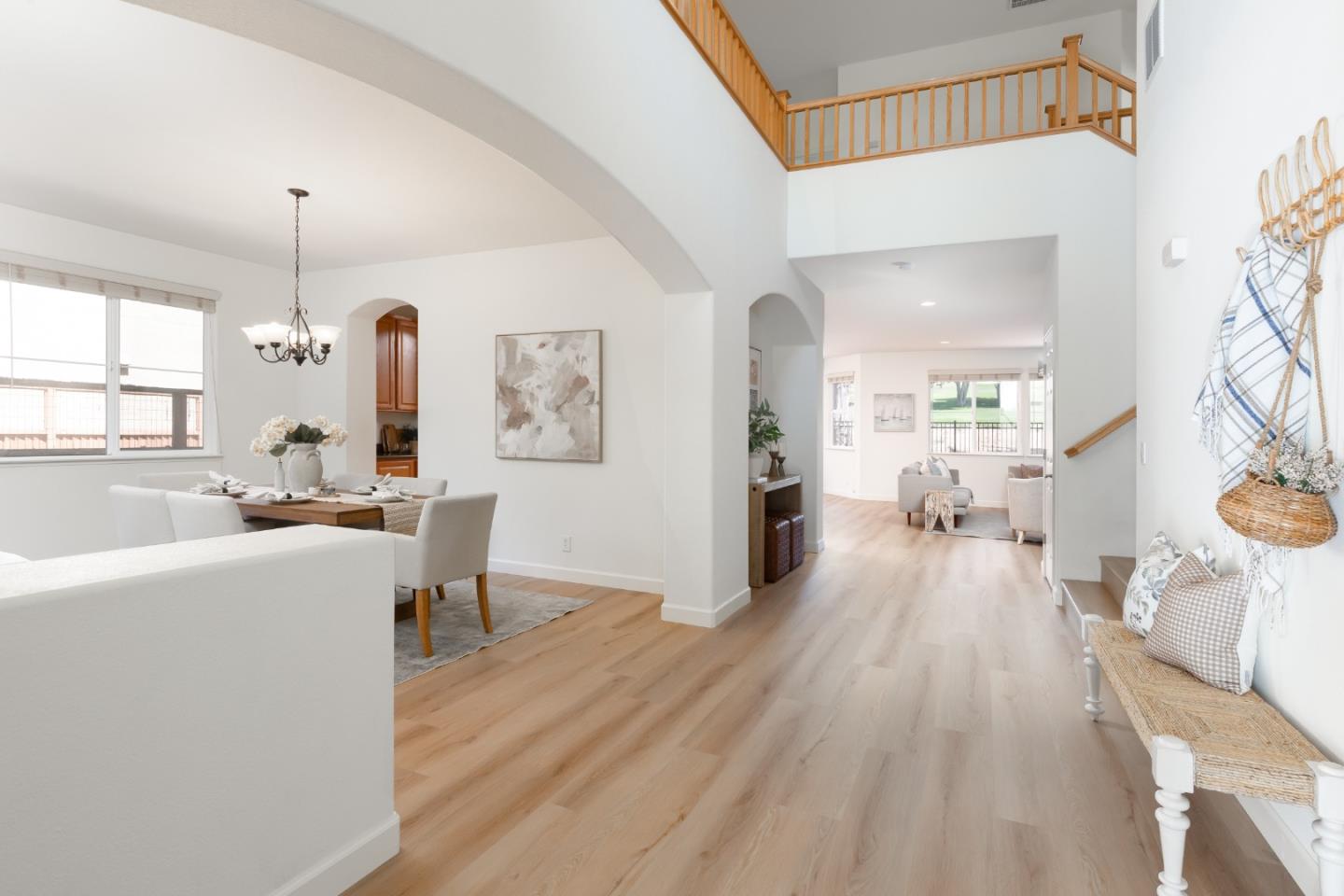 Open-plan dining area and entry with light wood floors and an upstairs landing.