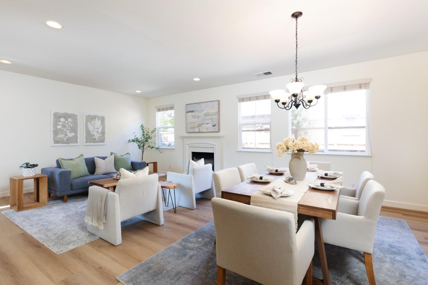 Open-plan living and dining room with a fireplace, blue sofa, and chandelier.