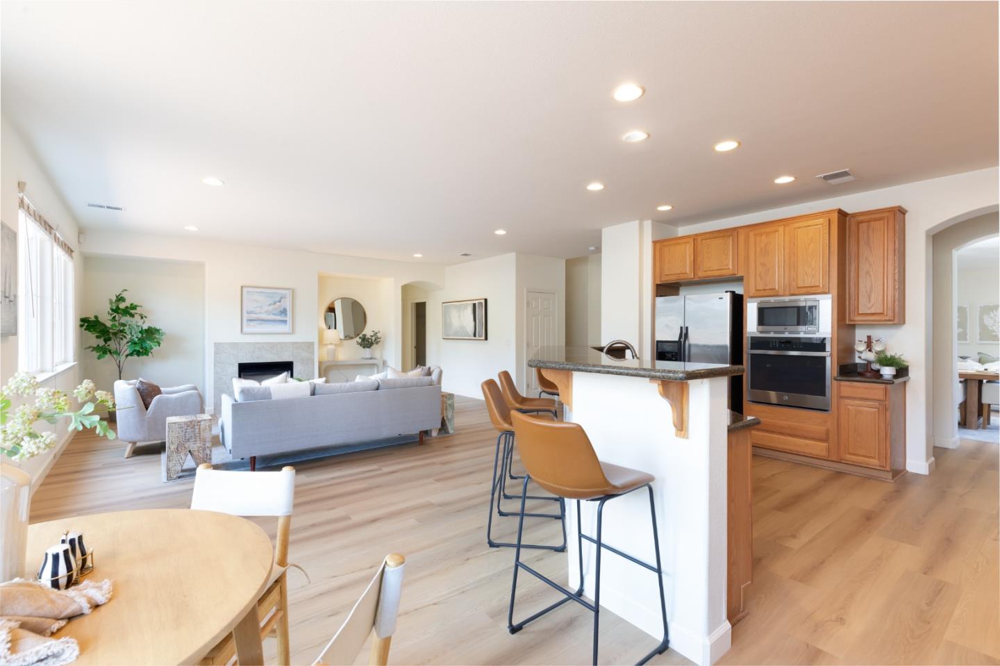 Open kitchen and living room with a breakfast island, wood cabinetry, and fireplace.