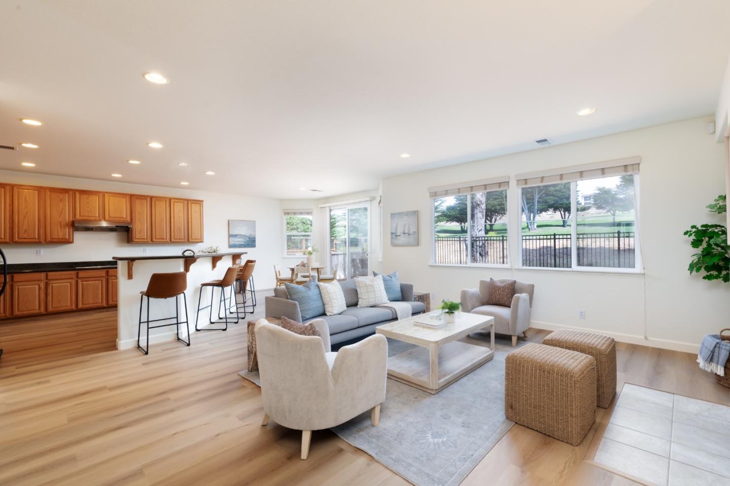 Open-plan living room and kitchen with a breakfast bar and large windows overlooking green grounds.
