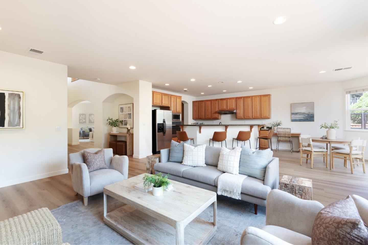 Staged open-plan living room with gray sofas, wood floors, and a kitchen breakfast bar.