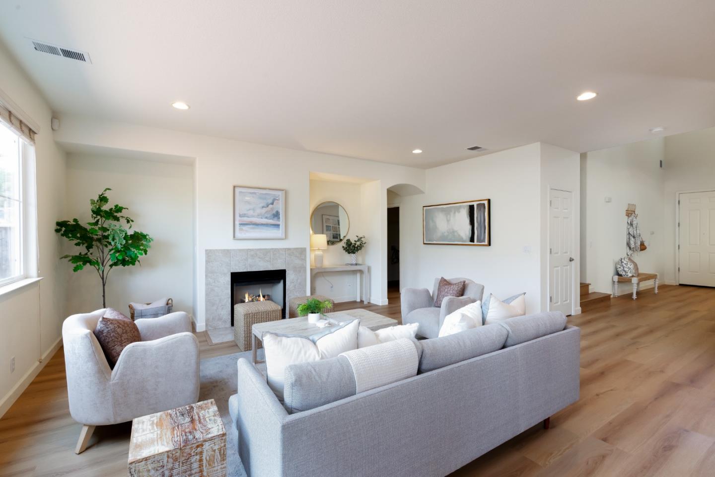 Furnished living room with a tiled fireplace, gray seating, and light wood floors.