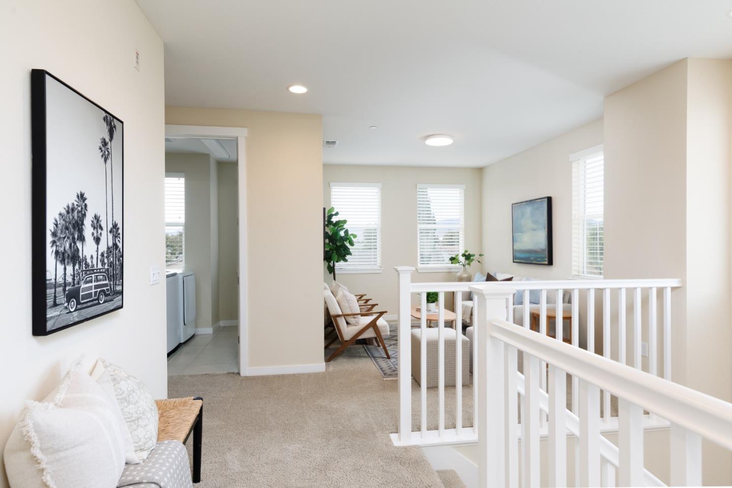 Upstairs landing with white stair railings, a cozy sitting area, and a laundry nook.