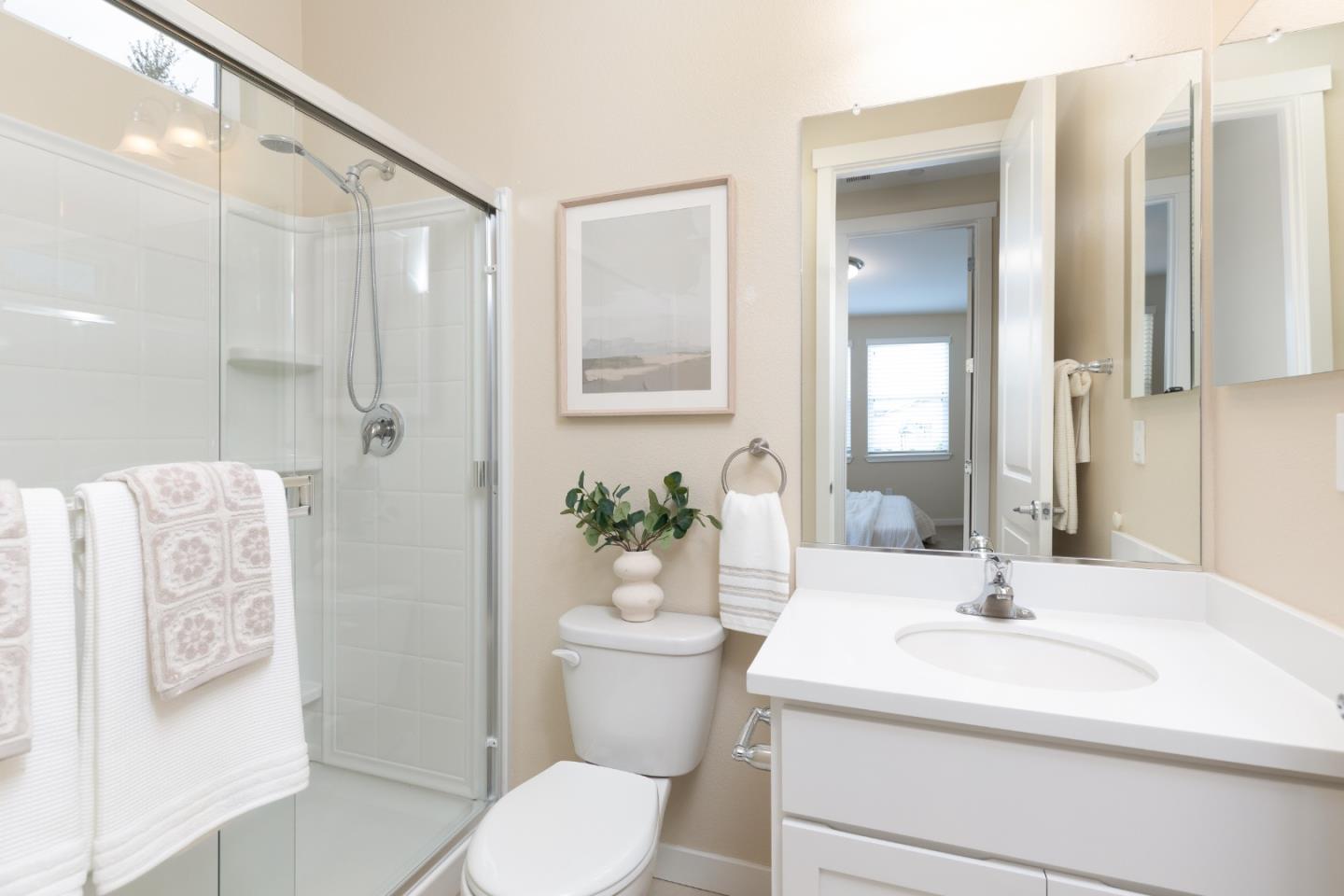 Bathroom with a glass shower enclosure, white vanity, and large mirror.