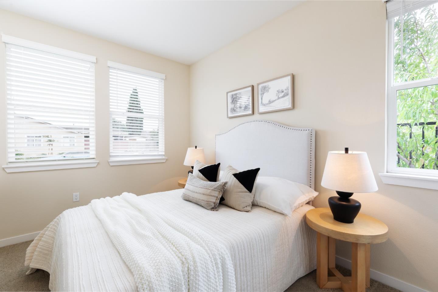 Bright bedroom with a white bed, upholstered headboard, and windows on two walls.