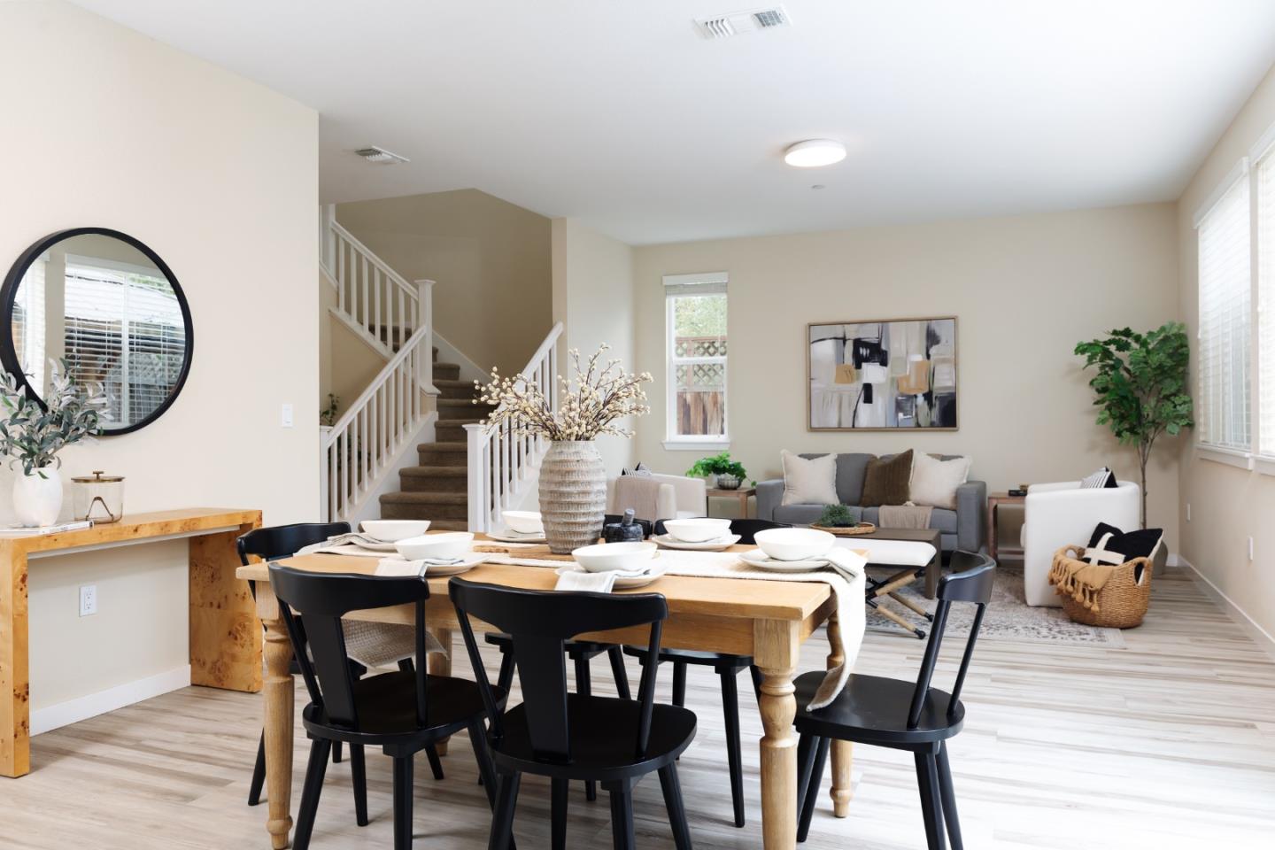 Dining area with a set wooden table, opening to a living room and staircase.
