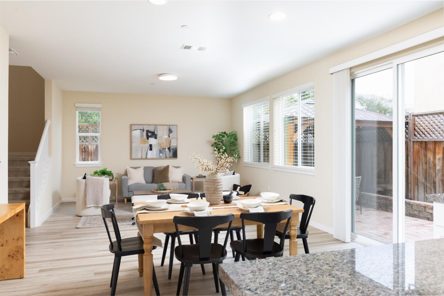 Dining and living area with a set table, gray sofa, and sliding glass doors to a patio.