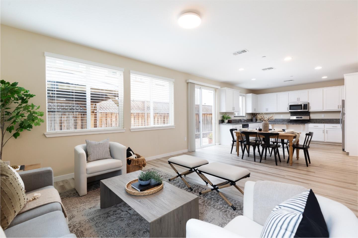 Open-plan living and dining area with a white kitchen, large windows, and sliding glass doors.