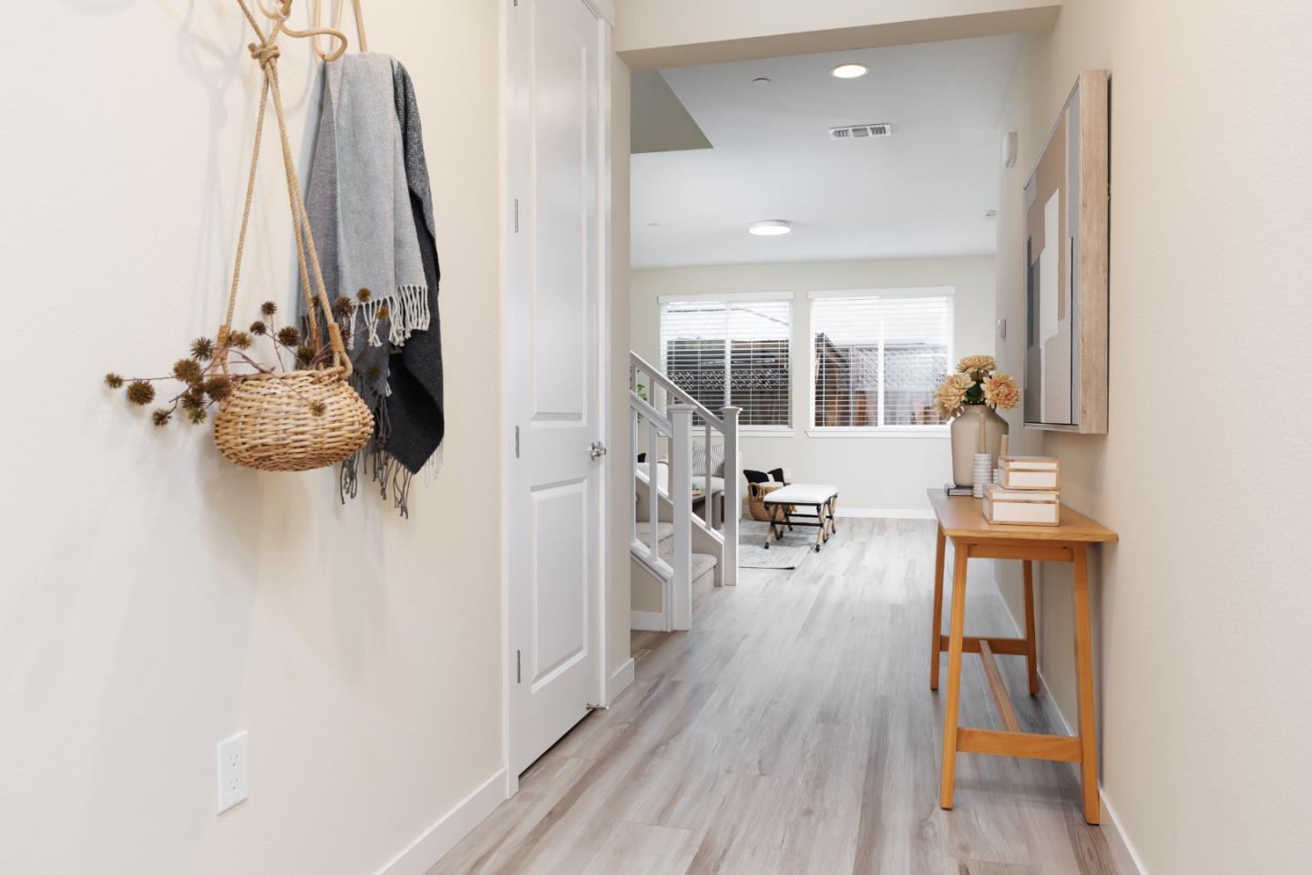 Bright hallway with pale flooring, a console table, and a view into the living area.