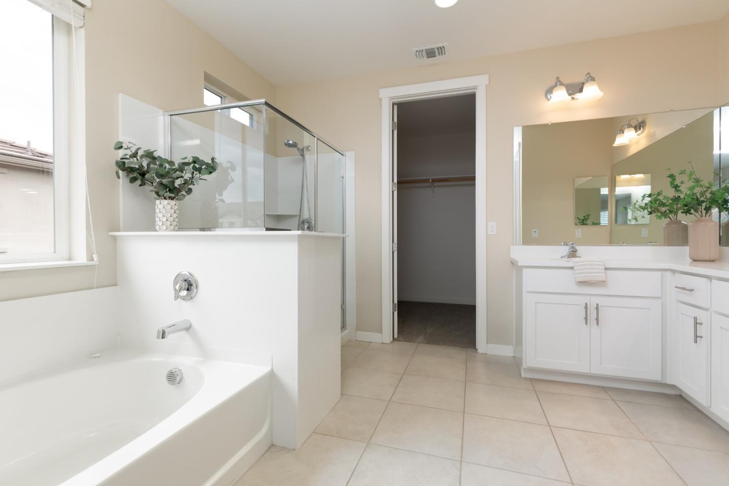 Bathroom with a soaking tub, glass-enclosed shower, and white vanity.