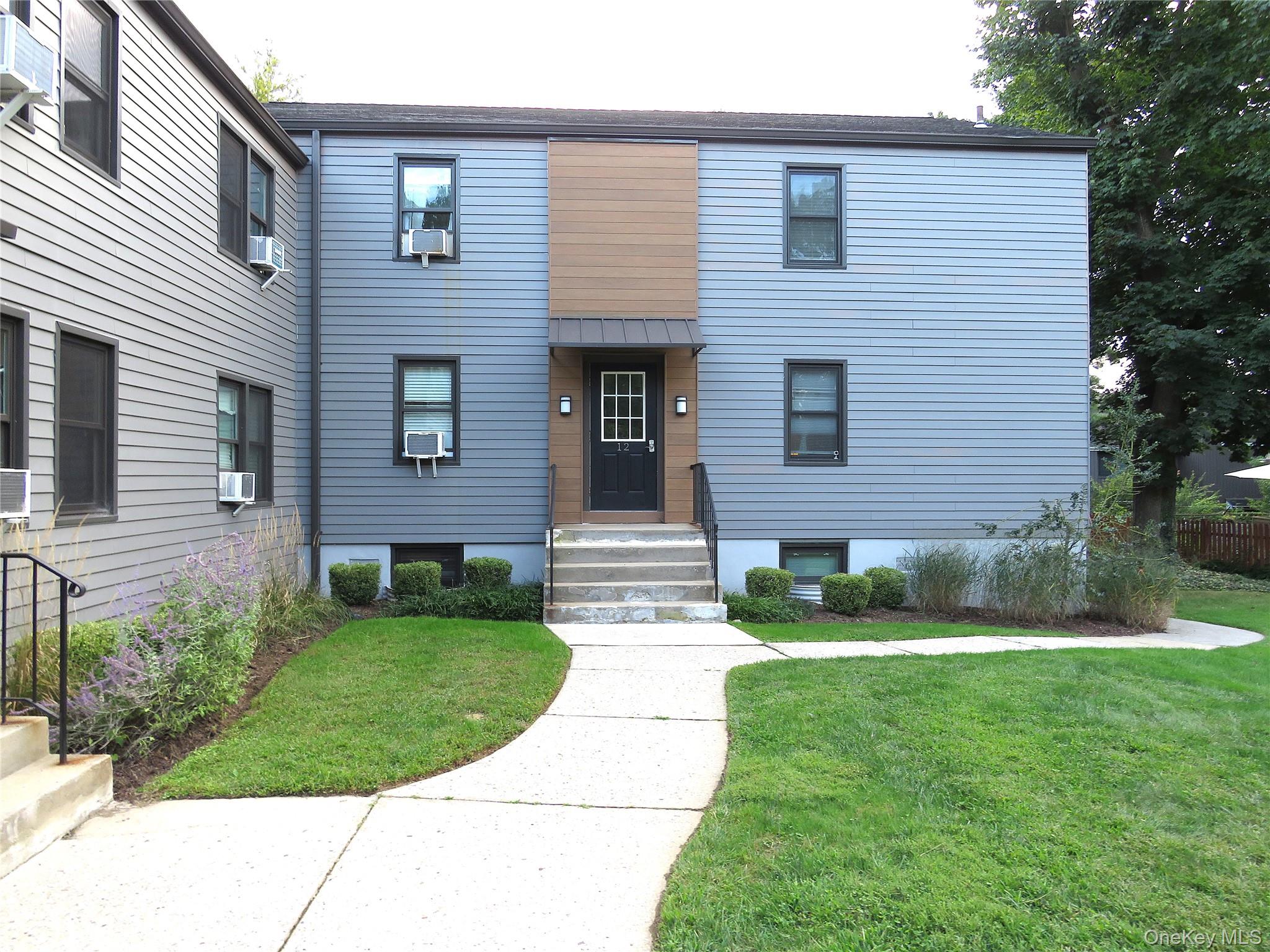 Blue-gray two-story home with a brown entry surround, front steps, and a curved walkway through the lawn.