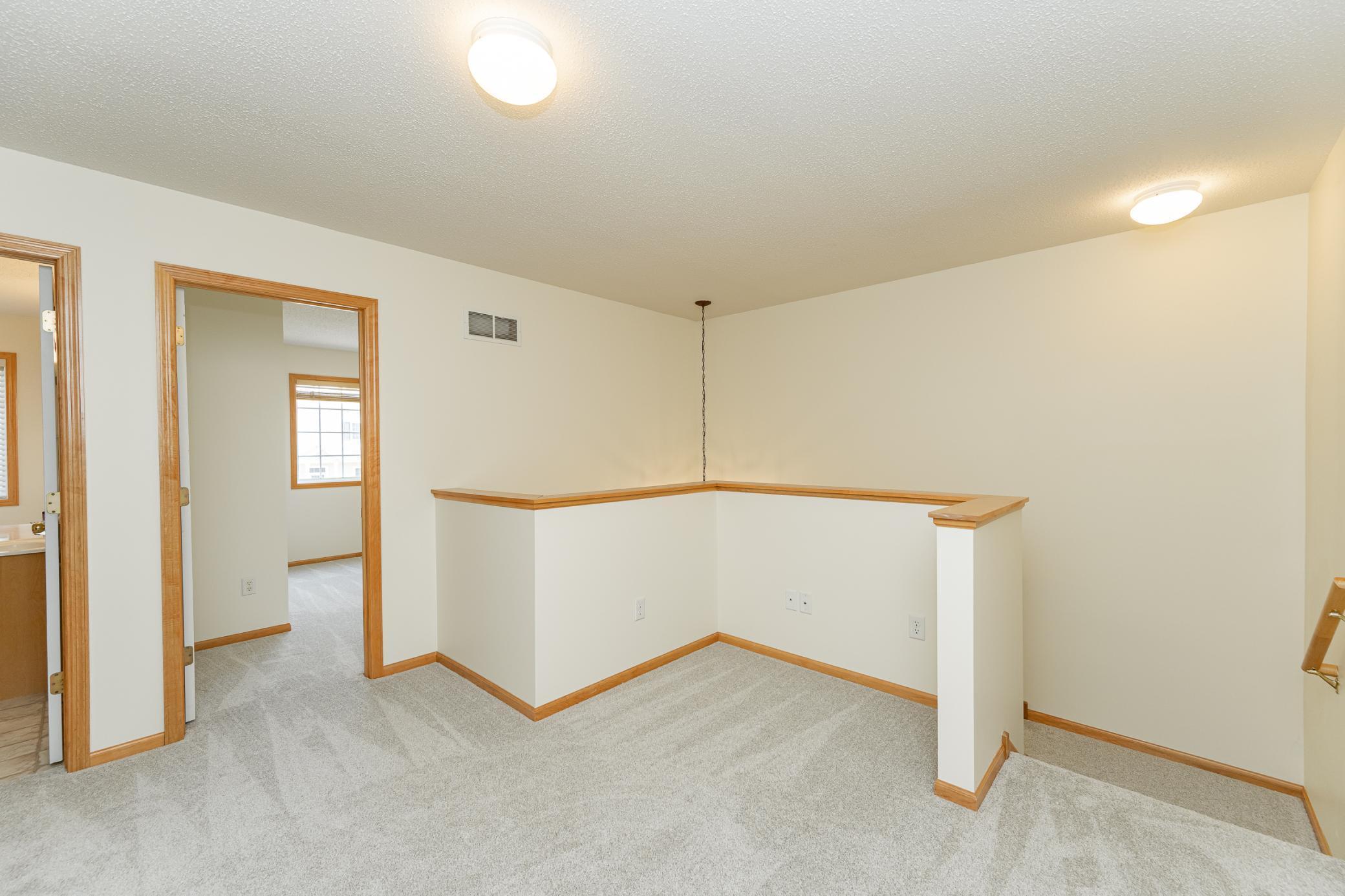 Carpeted landing with a half-wall railing and light wood trim.