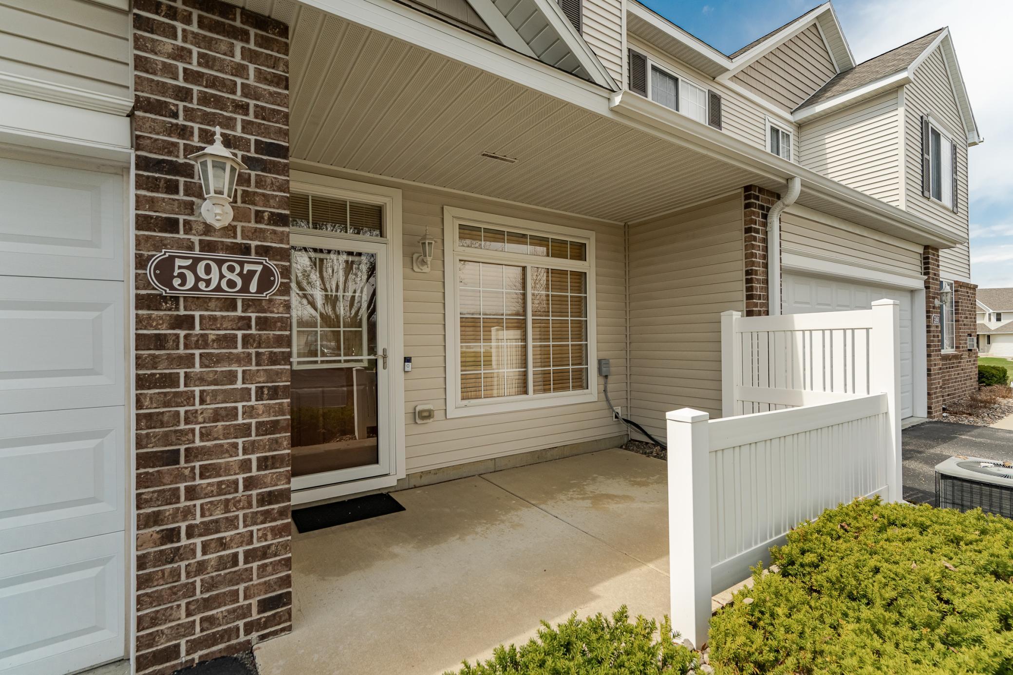 Home entrance with covered porch, brick accents, and white railing.